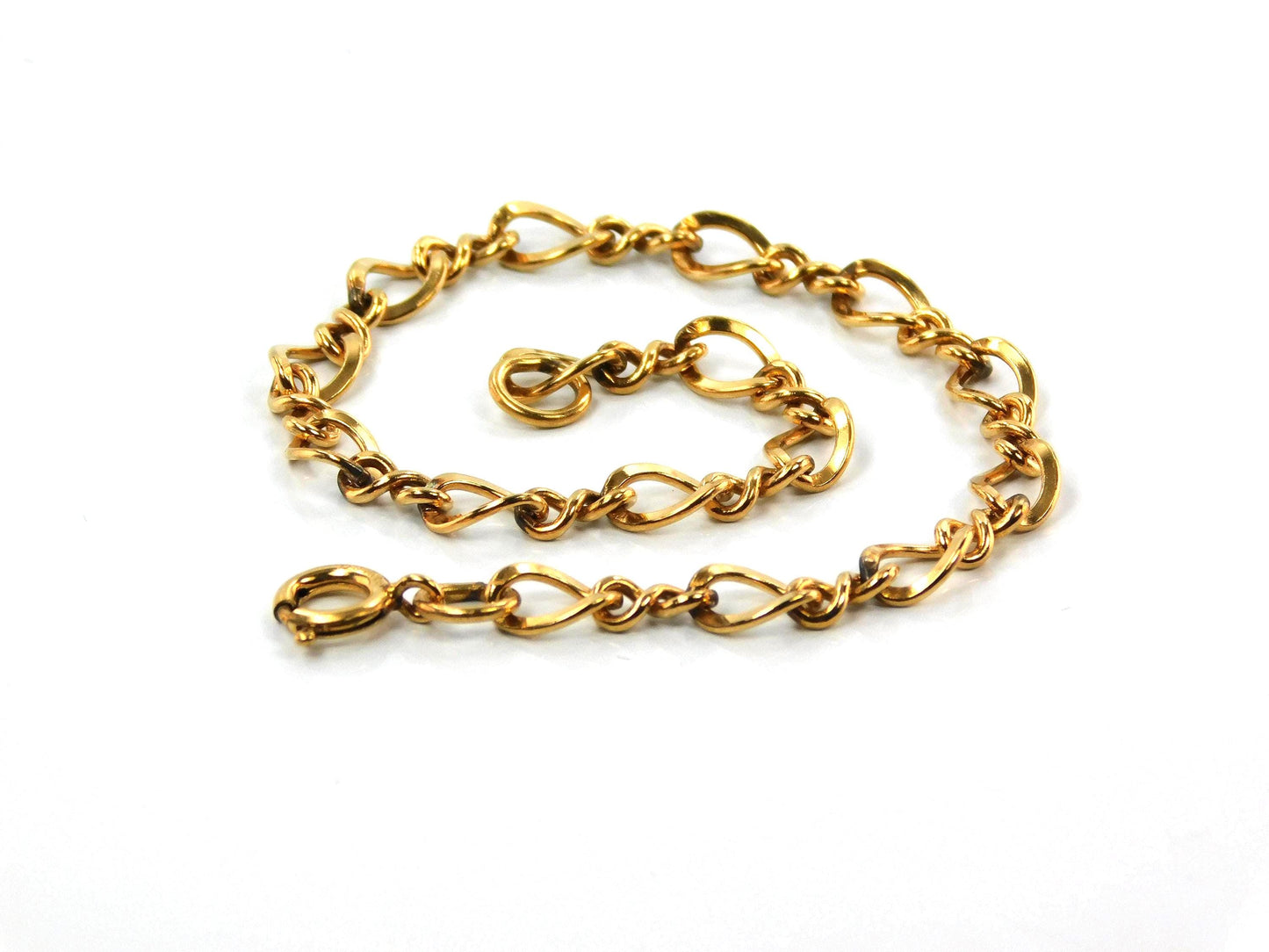 A close up of a vintage 14k yellow gold filled link bracelet with a spring clasp. The links shaped like number eight and plain links are interspersed with each other.
